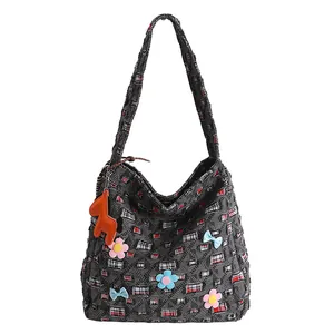 Detail der grauen Denim-Tasche mit Karomustern und orangefarbenem Pferdeanhänger