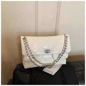 Detail of cream quilted messenger bag with shiny leather and rhinestone lock closure