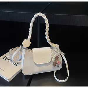 Detail of white square handbag with woven handle and elegant pearl charm on display