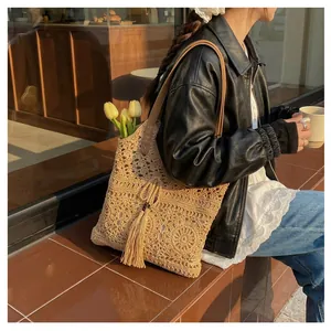 Close-up of beige crochet tote bag with fringe details and leather shoulder straps