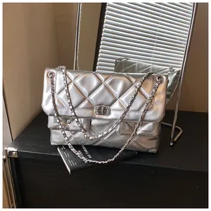 Detail of silver quilted chain bag with crystal lock on a modern minimalist tabletop