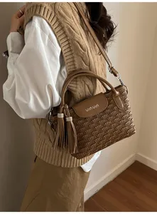 Detail of a brown pleated bucket bag with tassel ornament and metal hardware accents