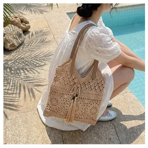 Detail of hollow-out woven tote bag with leather strap and tassel near a pool