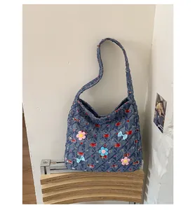 Detail der Denim-Einkaufstasche mit rot-weißen Karopatches und 3D-Blumendekor