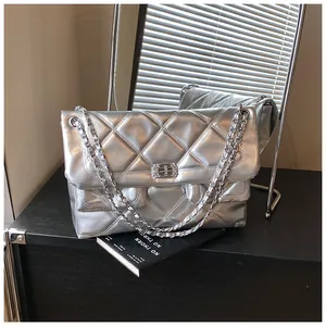 Detail of silver quilted crossbody bag featuring a rhinestone rotary lock and chain strap