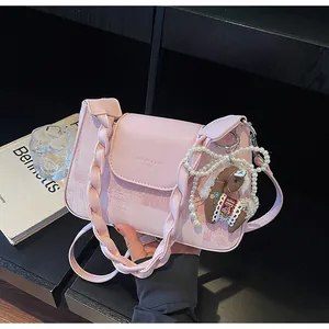 Detail of pink vintage crossbody bag with woven strap, horse charm and pearl bow