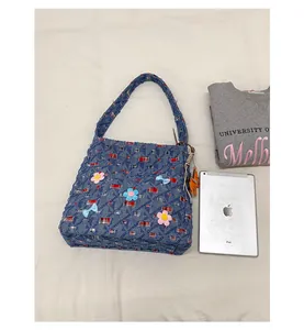 Detail der Denim-Einkaufstasche mit 3D-Blumenflicken und rot-blauem Karofutter
