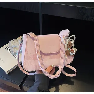 Detail of pink leather handbag with braided handle and pearl horse charm accessory