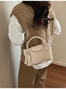 Detail of cream water-ripple bucket bag with woven texture, dual handles and fringe tassel