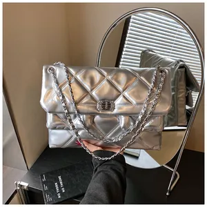 Close-up of silver quilted crossbody bag with crystal buckle and chain strap detail