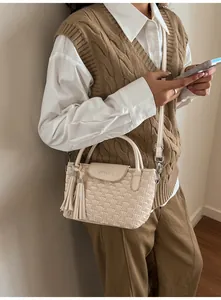 Detail of off-white pleated bucket bag with dual tassels and branding shown on model