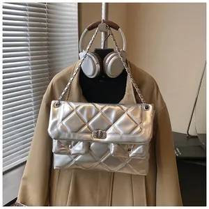 Detail of silver quilted crossbody bag with metal chain strap and turn-lock closure
