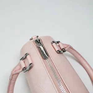 Close-up of pink faux leather bag featuring a silver metal zipper and solid rectangle puller