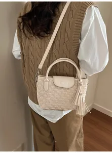 Detail of cream white bucket bag with pleated texture and adjustable strap on model