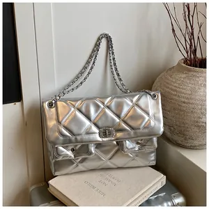 Detail of silver metallic quilted bag featuring dual pockets and CC-style metal twist lock