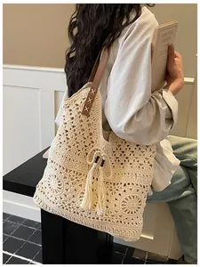 Detail of crochet tote bag featuring white woven pattern and brown leather straps