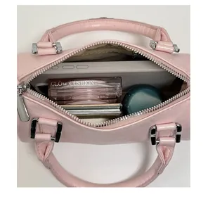 Interior view of pink cylinder bag showing capacity for cosmetics and a tablet