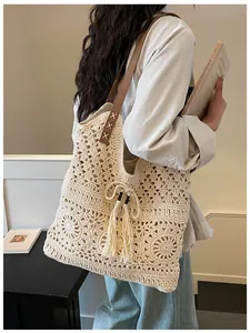 Detail of hand-woven cream tote bag featuring floral crochet patterns and fringe tassels