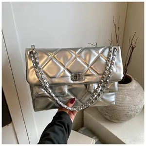 Detailed close-up of large quilted silver crossbody bag with metallic chain strap and twist lock