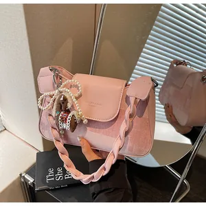 Detail of pink crossbody bag with decorative pearls and small brown plush horse charm
