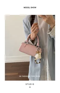 Detailed view of a pink faux leather handbag with silver hardware and plush charm accessory