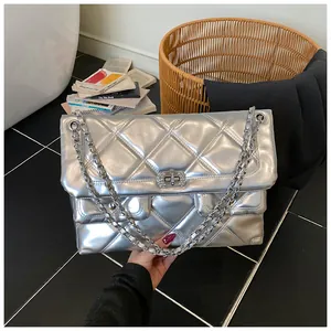 Detailed view of silver quilted shoulder bag with rhinestone rotary lock and chain strap