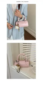 Detail of pink cylindrical handbag with plush charm and beaded chain accessory