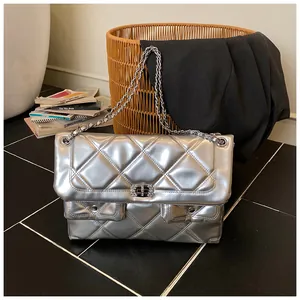 Close-up of silver quilted crossbody bag with metallic chain and diamond lock detail