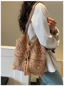 Close-up of beige crochet cotton tote bag with hollow patterns and tassel drawstring closure