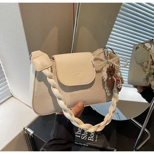 Close-up of beige shoulder bag with braided handle and embroidered pony charm