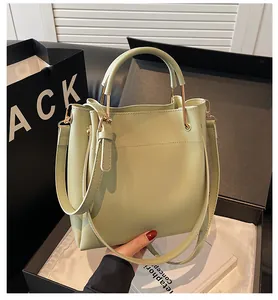 Dettaglio della borsa a secchiello verde chiaro con finitura in pelle liscia in una scatola
