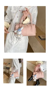 Detailed macro shot of pink lychee grain leather handbag with plush rabbit keychain