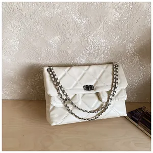 Detailed close-up of quilted beige leather crossbody bag with chain strap and metal lock