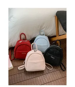 Mini velvet backpacks in red, blue, pink, and black colors displayed on wooden floor