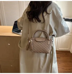 Detail view of beige bucket bag featuring water ripple texture and dual metal tassels