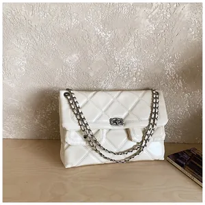 Detail shot of cream quilted crossbody bag with silver chain strap and polished finish