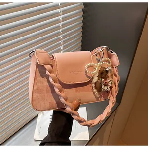 Detail of pink vintage square bag with braided strap, pearl chain and horse pendant