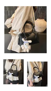 Detail of black pebbled leather Boston bag with a cute plush rabbit charm accessory