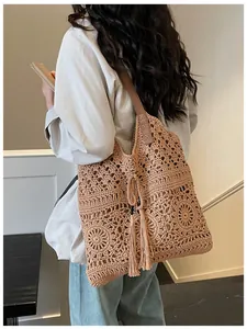 Detail of hand-woven hollow pattern tote bag with tassels and leather strap shown on model
