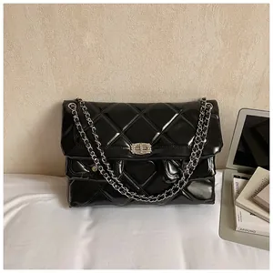 Close-up of quilted glossy leather texture and silver metal twist lock on the crossbody bag