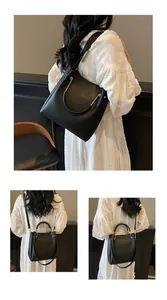 Dettaglio di una borsa a secchiello nera con manico dorato e trama in ecopelle