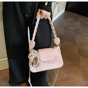 Close-up of pink canvas handbag with woven handle and a pearl pony charm detail