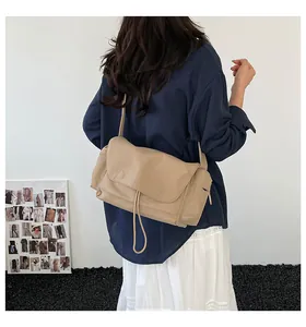 Dettaglio della borsa a tracolla in pelle kaki con cuciture decorative e patta morbida