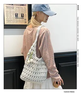 Detail of white handmade crochet tote bag featuring floral pendant and woven mesh texture