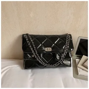 Detail of glossy quilted crossbody bag with silver chain and rhinestone twist lock