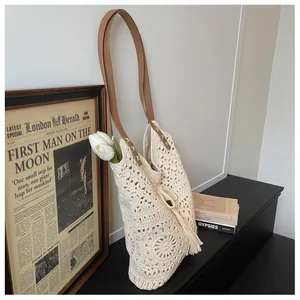Detail of crochet tote bag featuring floral pattern, tassel charm and brown leather strap