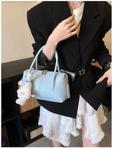 Detail of light blue Boston bag with lychee texture and cute bear pendant accessory