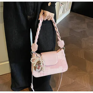 Pink crossbody bag featuring woven handle, texture finish, and cute cartoon charm detail