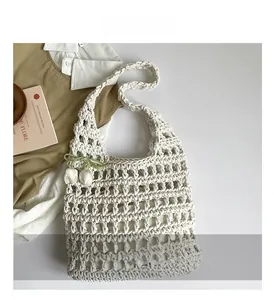 Detail of hollow woven tote bag in cream white with floral pendant and thick cotton texture