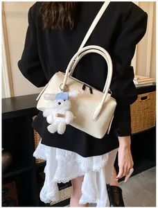 Detail view of cream Boston bag with lychee texture and plush rabbit pendant charm